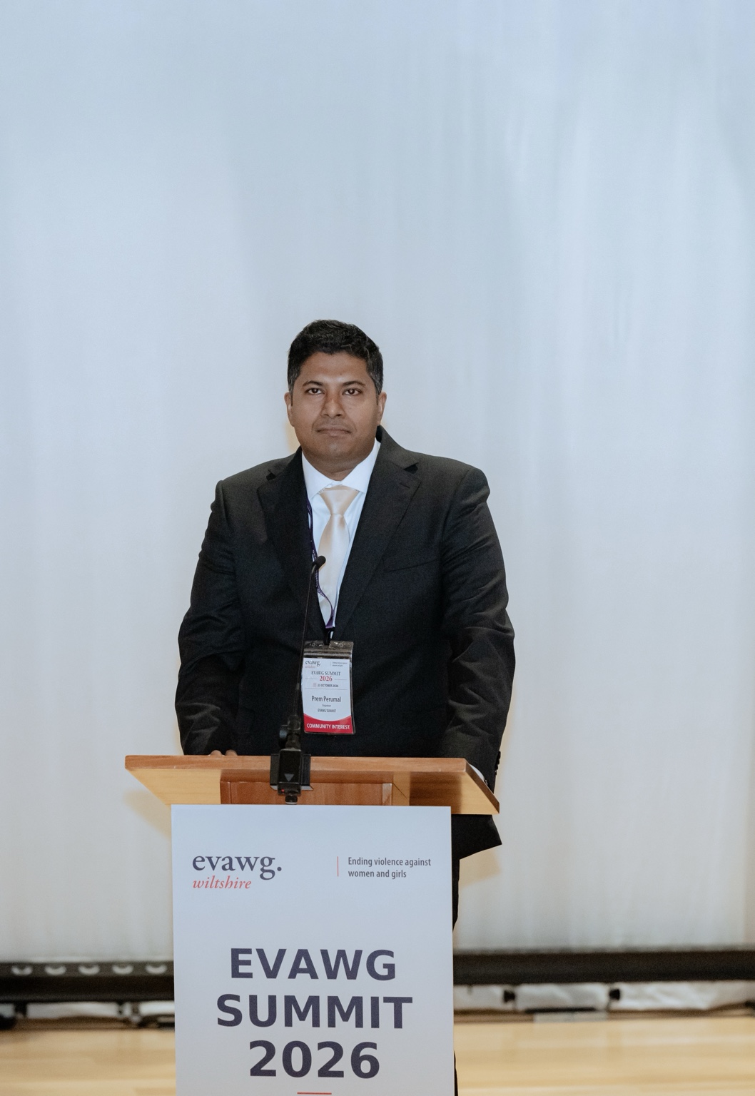 Prem Kumar Perumal at the lectern bearing the EVAWG Summit 2026 sign